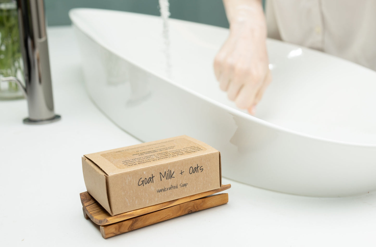 wooden soap dish that curves up on both sides with a boxed soap sitting on it in front of a bathroom sink